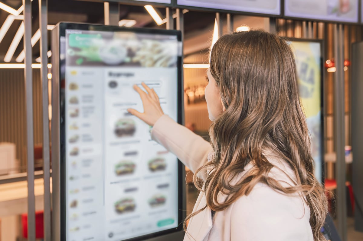 A customer using a large touchscreen kiosk to order in a modern restaurant